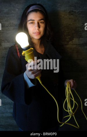 Young woman holding yellow lamp with long wire in hand Stock Photo