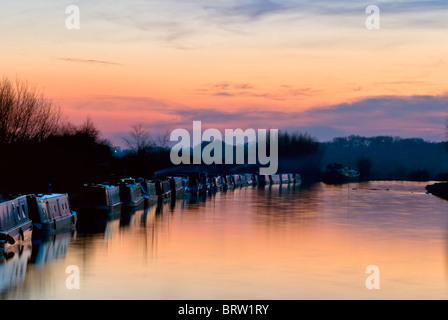 Canal boats with reflection and orange sunset at Gloucester & Sharpness canal on a beautiful still evening, taken at Slimbridge Stock Photo