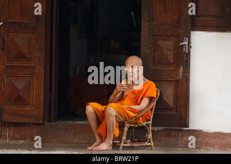 elderly monk smoking a cigarette Stock Photo