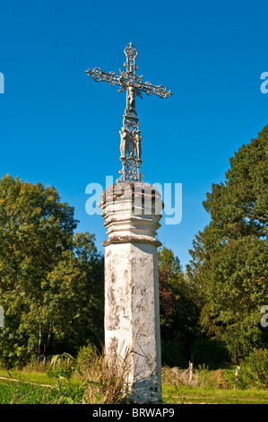 Roadside decorative wrought iron cross on hexagonal carved stone plinth - France. Stock Photo