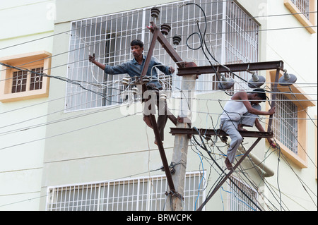 Indian Electrician working up an Electricity pylon in the streets of Puttaparthi, Andhra Pradesh, India Stock Photo