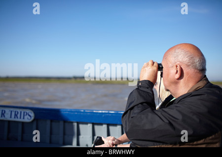 Older bald man in a boat looking through binolulars Stock Photo