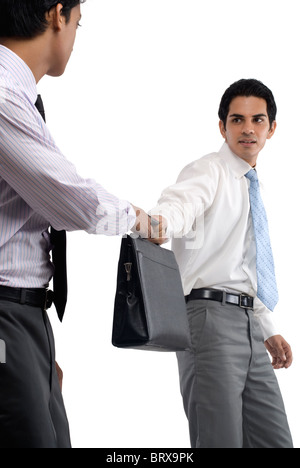 One businessman giving a bag to the other Stock Photo