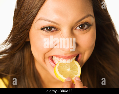 Close up of Hispanic woman biting lemon slice Stock Photo