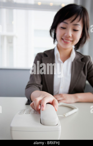 Businesswoman Reaching for Telephone Stock Photo