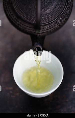 Close up of Japanese green tea being poured from teapot into cup Stock Photo