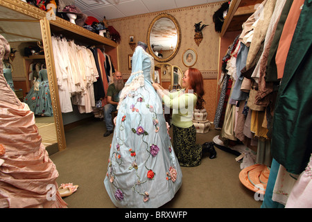 Seamstress adjusting 18th century silk gown costume for Carnival, with period costumes in seamstress shop Stock Photo