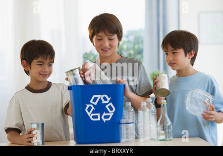 Mixed race brothers recycling plastic bottles and tin cans Stock Photo