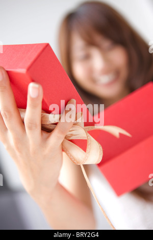 Young woman opening present box, close up, white background, differential focus