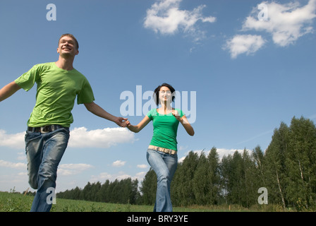 Young couple running trough field Stock Photo