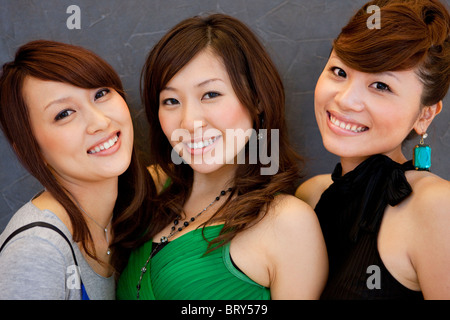 Portrait of three young women, smiling and looking at camera, black background Stock Photo