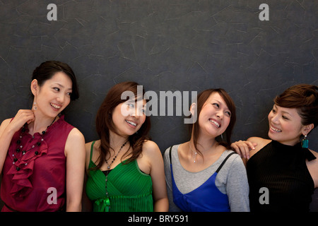 Four young women, three looking at the other, black background Stock Photo
