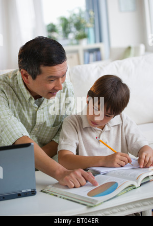 Father helping son with homework in living room Stock Photo