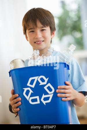 Smiling mixed race boy holding recycling bin Stock Photo