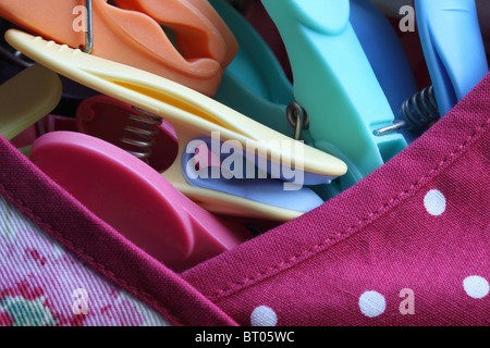 Close up of multi-coloured plastic pegs in a peg bag Stock Photo
