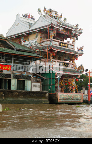 Typical Bangkok houses on stilts along khlong canal, with a small spirit house in the front.Bangkok, Thailand, September 2010 Stock Photo