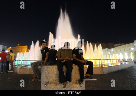 Young Kurdish men gathered around the water fountain in the middle of Parki Shar, or City Park bellow the old citadel in the city of Erbil also spelled Arbil or Irbil the capital city of Kurdistan Region in northern Iraq. Stock Photo