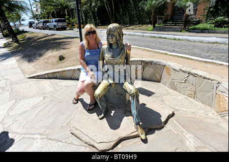 A tourist poses with the Brigitte Bardot statue in Buzios, she is credited with discovering Buzios in the 1960's Stock Photo