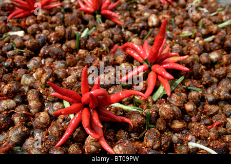 Snails and red hot chili peppers are for sale on a street vendor's cart in Phnom Penh, Cambodia. Stock Photo