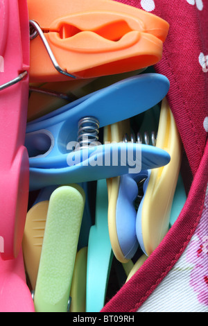 Close up of multi-coloured plastic pegs in a peg bag Stock Photo