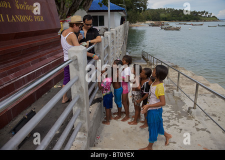 A group of little girls waiting to be paid for jumping into the sea from a pier at Rawai, Phuket Thailand Stock Photo
