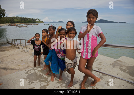 A group of little girls who like jumping into the sea from a pier after school, posing for the camera at Rawai, Phuket Thailand Stock Photo