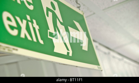 close up of green fire exit sign hanging from roof Stock Photo