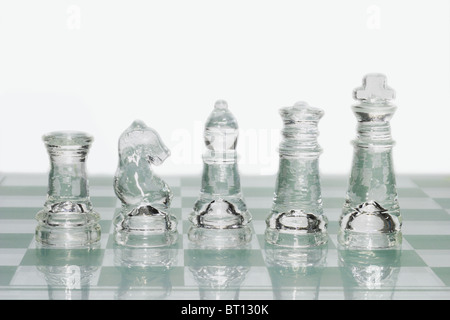 Glass chess pieces on chessboard against white background Stock Photo
