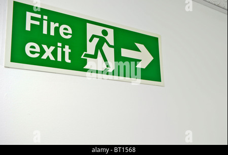 green fire exit sign mounted on wall Stock Photo