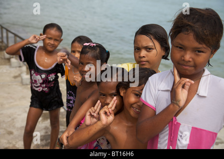 A group of little girls who like jumping into the sea from a pier after school,posing for the camera at Rawai, Phuket Thailand Stock Photo