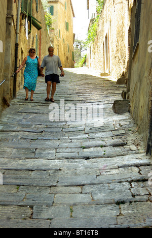 Couple holding hands walking down a cobbled street in Montalcino, Tuscany Stock Photo