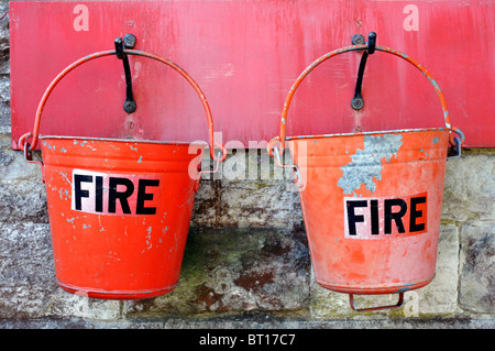 two bright red emergency fire buckets hanging at corfe railway station dorset england uk Stock Photo