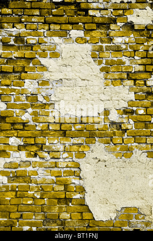Old yellow wall with cracks and grey patches of plaster in portrait format Stock Photo