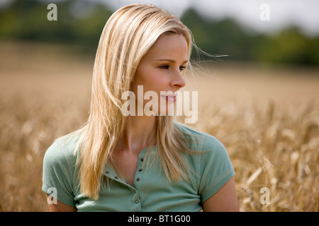 A woman sitting in a wheatfield in summertime Stock Photo