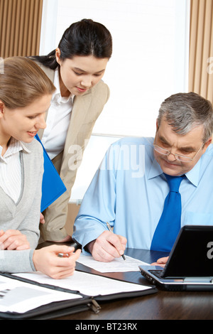 Three businesspeople examining a contract in office Stock Photo