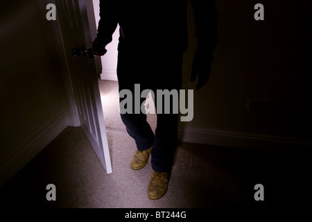 Man wearing old boots entering a dark room turning the handle as he walks in Stock Photo