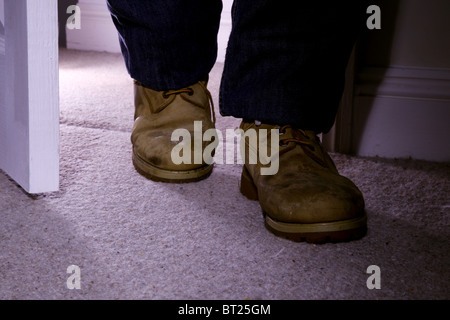 Mens feet with dirty old boots walking into a room Stock Photo