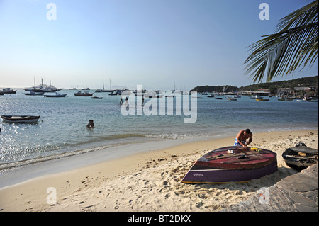 A man repairs his boat on Canto Beach Buzios Stock Photo