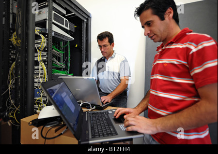 IT personnel on laptops fixing some problems with the main server Stock Photo