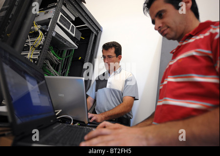 IT personnel on laptops fixing some problems with the main server Stock Photo