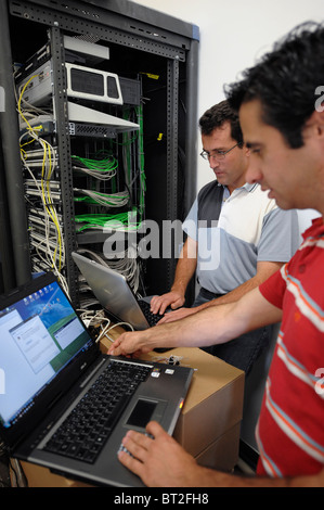 IT personnel on laptops fixing some problems with the main server Stock Photo