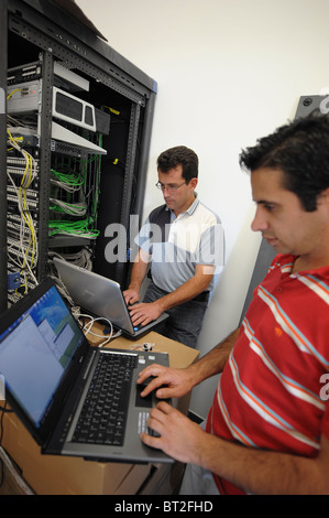 IT personnel on laptops fixing some problems with the main server Stock Photo
