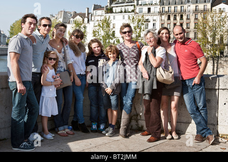French matriarch poses for family portrait on Pont de la Tournelle Paris with adult children their spouses & her grandchildren Stock Photo