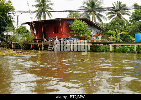 Typical Bangkok houses on stilts along khlong canal, with a small spirit house in the front.Bangkok, Thailand, September 2010 Stock Photo