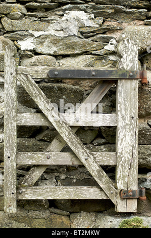 Old wooden gate closed against stone wall Stock Photo