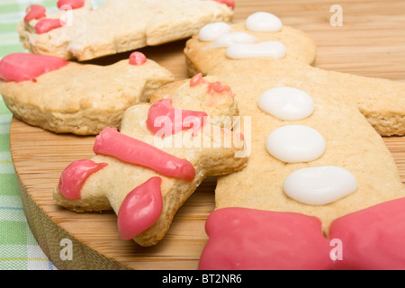 Gingerbread biscuits decorated by child on wooden board from low perspective. Stock Photo