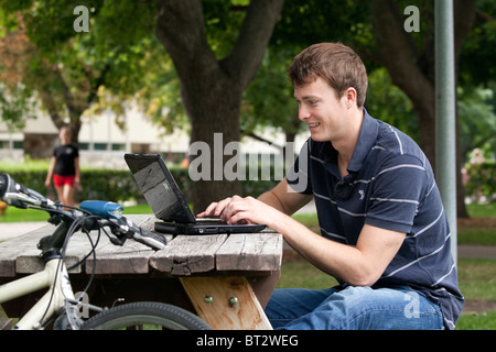 Young man in his twenties using a laptop computer outdoors Stock Photo
