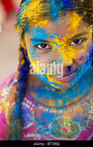 Young Indian girl covered in coloured powder pigment. India