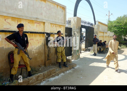 Police officials stand guard at a polling station at Orangi Town as security has been tightened during the by-election for PS-94 Stock Photo