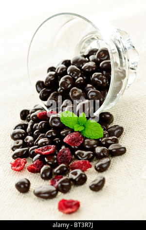 Chocolate covered cranberries spilling from glass dish Stock Photo